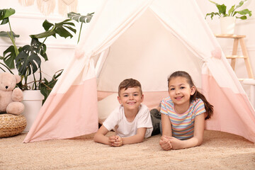 Cute little children in toy wigwam at home © New Africa