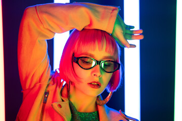 Portrait of glamorous woman on party under glowing neon light. Nightclub, trendy outfit. Teenager, zoomer Z-generation. Lady with sunglasses and massive hoops earrings