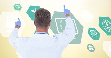 Composition of male doctor over digital icons on yellow background