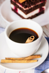 Cup of coffee with cinnamon in a close-up on a napkin, cinnamon sticks