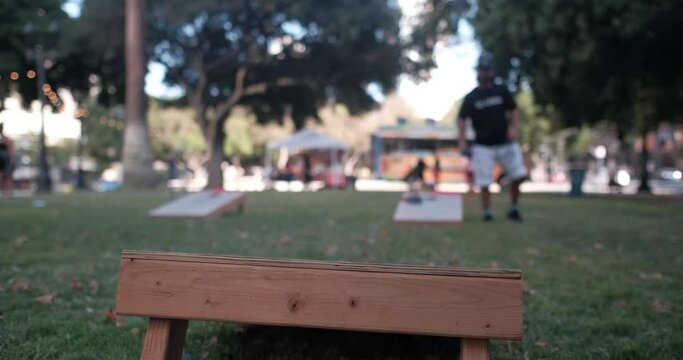 Young male playing cornhole outside at the park