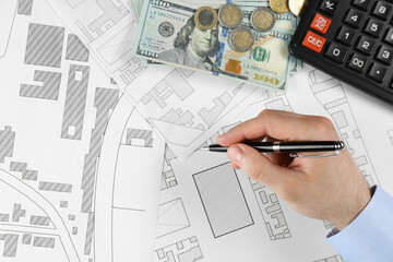 Cartographer with calculator and money drawing cadastral map, closeup