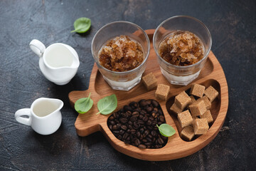 Wooden serving tray with coffee granita and its ingredients, studio shot on a dark brown stone background