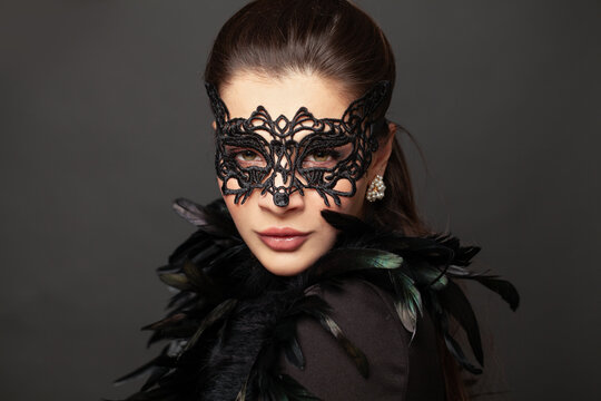 Beauty model woman with stylish black carnival mask. Glamorous beauty in creative masquerade party dress on black background