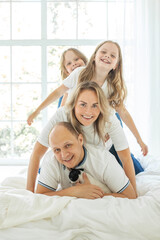 Mother, father and girls stacked on top of each other. Family with two daughter playing at home. Happy family portrait