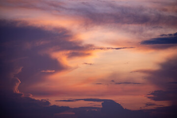 River IJssel in shadow through silhouetted trees with dark patches of clouds in radiant vibrant colorful magenta, yellow and orange sunset colors. Weather conditions and climate concept. 