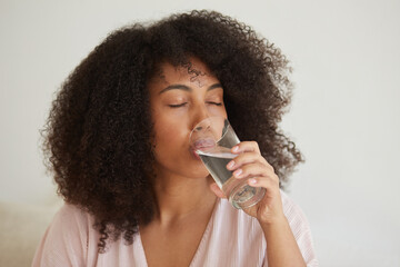 A young black lady hold a glass of clean pure mineral water, improve health and wellbeing, avoid dehydration, modern women are restless, enjoy aqua for body hydration, beauty concept