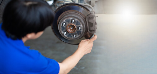 Asian man mechanic changing car wheel at Car maintenance and auto service garage. Young male worker...