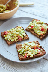 Vegetarian green sandwiches with avocado and tomatoes chopped on wooden grey table