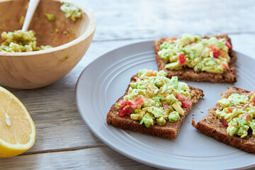 Vegetarian green sandwiches with avocado and tomatoes chopped on wooden grey table