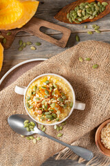 Millet porridge with pumpkin slices and seeds, walnuts in a ceramic bowl in a rustic style. Delicious and healthy autumn breakfast	