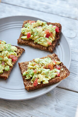 Vegetarian green sandwiches with avocado and tomatoes chopped on wooden grey table