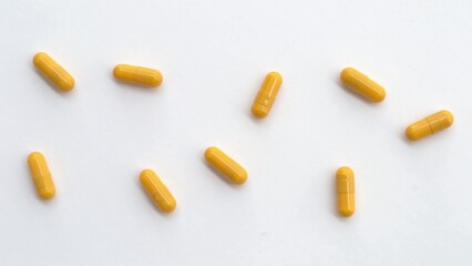 Yellow pill capsules are scattered on a white background. Isolated