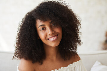 A serene, young mixed race woman with clear skin and a beautiful smile smiling, feeling calm and confident, looking at the camera, portrait