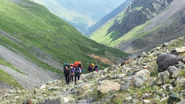 A group of tourists with large backpacks climbs the mountain. Climbing Kazbek from the north, from the side of Russia. Hike across the Caucasus.