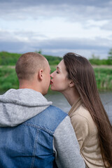 sweet couple sitting by the water river on green grass. attractive brunette woman and bald man outdoors. true love, happy family, romance, successful marriage