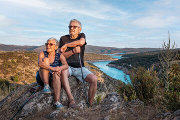 Senior couple in the mountains. Enjoying a walk in the country. Happy couple over 60 years old and outdoors and with a river in the background. Portrait and landscape in the Community of Madrid