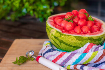 sweet and juicy watermelon small balls, served using the skin as a bowl over a wooden table. Summer food concept. Selective focus