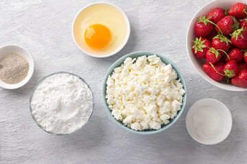Ingredients for homemade cottage cheese gnocchi with strawberry sauce: cottage cheese, strawberry, rice flour, egg, sugar, vanilla sugar, baking powder on a light gray background, top view