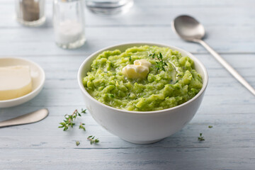 Delicate mashed potatoes with green peas, flavored with butter, spices and thyme on a light blue background. delicious homemade food