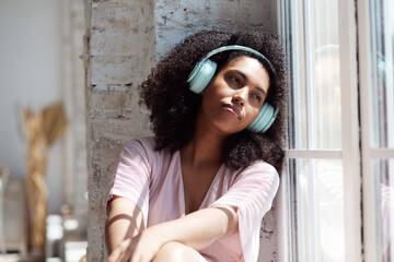 A lovely mixed-race woman listens to calming music on her phone and is charmed by the positive feelings. A vacation from freelance work and a search for inspiration and creativity