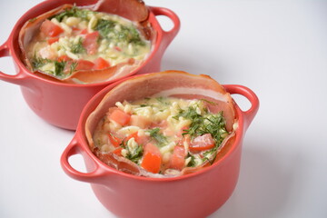 Proсess of cooking Omelette  with bacon, grated parmesan and greens. Raw beaten egg yolks  with ingredients in ceramic cocotte