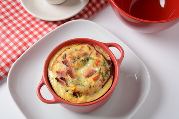 Omelette  with bacon, grated parmesan and greens in ceramic cocotte. Tasty breakfast