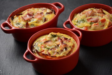 Omelette  with bacon, grated parmesan and greens in ceramic cocotte. Tasty breakfast