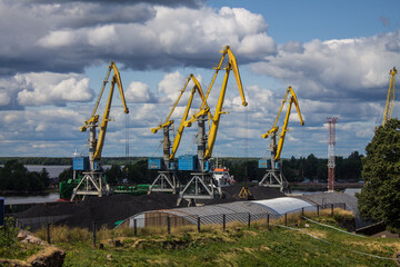 Fototapeta na wymiar yellow cargo cranes on the background of a blue cloudy sky