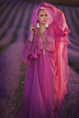 beautiful young girl in a pink dress walks in a lavender field