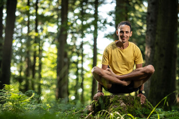 Naklejka na ściany i meble Junger Mann mit dunkler Haut im Lotussitz beim Yoga im Wald in der Natur