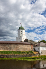Fototapeta na wymiar VYBORG, Leningrad REGION, RUSSIA-JULY, 19, 2021: the facade of a medieval fortress with a white Olaf tower surrounded by water on a cloudy summer day in the old town