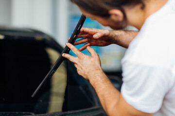 Technician and mechanical changing windscreen wipers on a car station. Car maintenance and auto service garage concept.