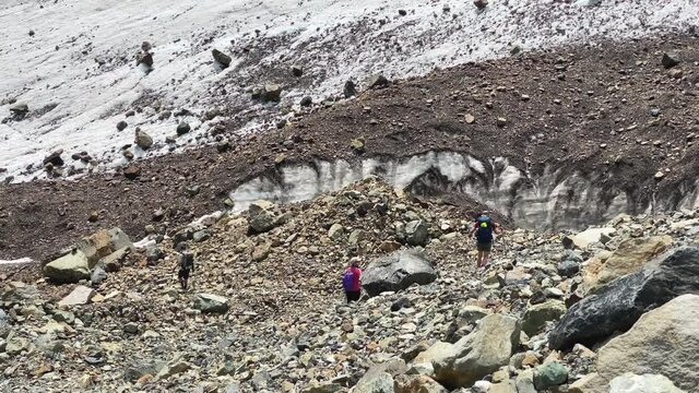 Three tourists descend the kurumnik to the Maili glacier, North Ossetia. Climbing Kazbek from the north, from the side of Russia. Hike across the Caucasus.