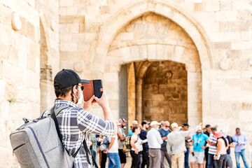 Fototapeta na wymiar Young digital nomad taking pictures with his mobile phone in the old city of Jerusalem.