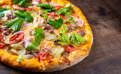 Pizza with Mozzarella cheese, Bolognese sauce, minced meat, bacon, tomato and vegetables. Italian pizza on wooden background.