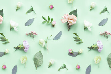 Floral pattern with pink roses, white flowers, branches, leaves and petals on green background. Flat lay, top view