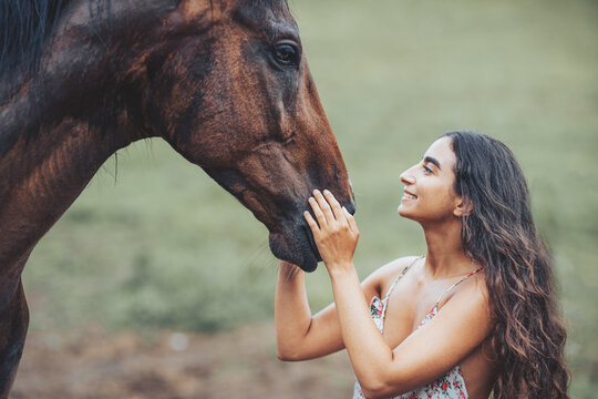 Portrait of woman and horse outdoors. Woman stroking a horse.