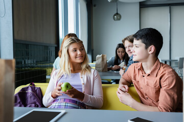 teenage friends talking during lunch break in school canteen