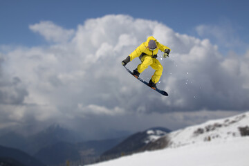 Snowboarder jumping in the mountains, extreme winter sport.