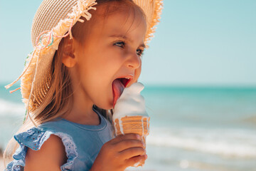 Cute little girl in a straw hat eating soft melted butter ice cream in a waffle glass on the...