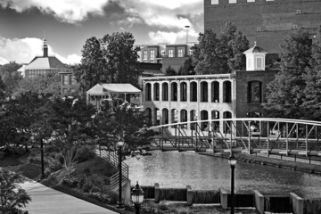 Black and white picture of buildings and river with bridge in park