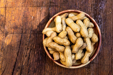 A lot of peanuts on a plate and  wooden background