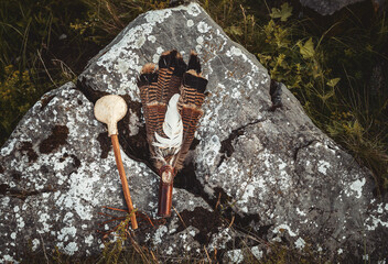 Shamanic rattle and shamanic feathers on denim in nature.