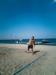Man playing volleyball on the beach by the sea
