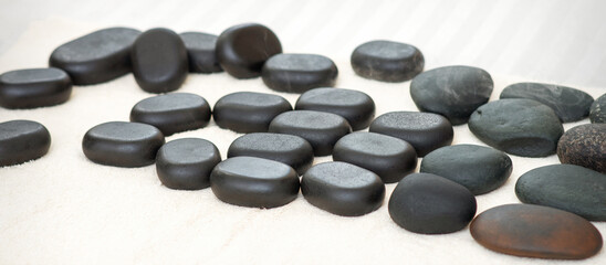 Many black massage stones lying isolated on the towel on the table