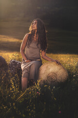 beautiful shamanic girl playing on shaman frame drum in the nature.