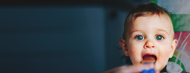 Portrait of a Baby Boy with Blue Eyes eating food with spoon at home