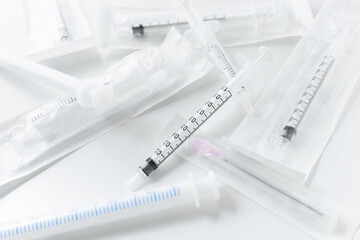 Pile of medical syringes, some still in packaging on white background