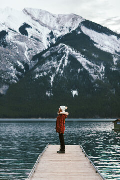 Woman standing on lake pier against mountains